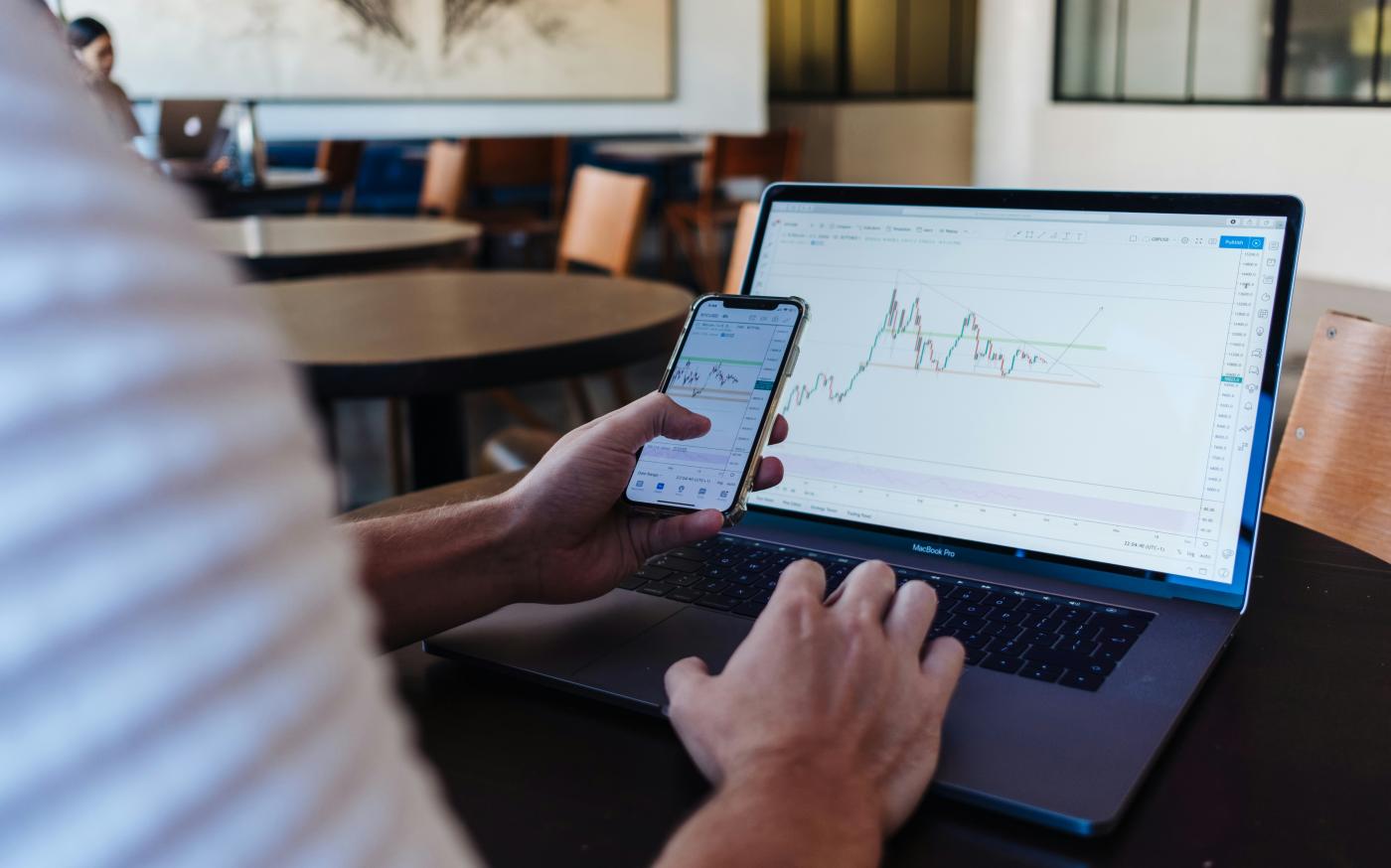 person using smartphone and MacBook Pro by Jason Briscoe courtesy of Unsplash.