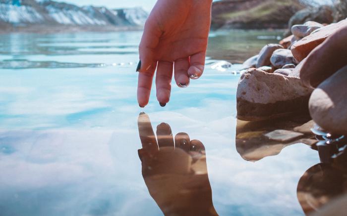 person with brown nail polish holding stones near body of water during daytime by Mohammad Alizade courtesy of Unsplash.