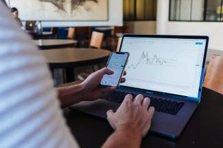 person using smartphone and MacBook Pro by Jason Briscoe courtesy of Unsplash.